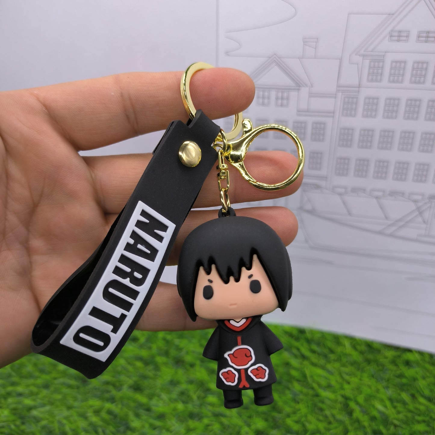 Breloc cu personajul Sasuke Uchiha îmbrăcat în haine Akatsuki în fundal principal