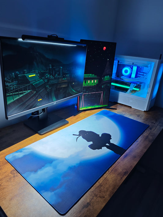 Mousepad Naruto cu personajul Itachi de mari dimensiuni privit din ansamblu, pe birou, cu PC de gaming si 2 monitoare.