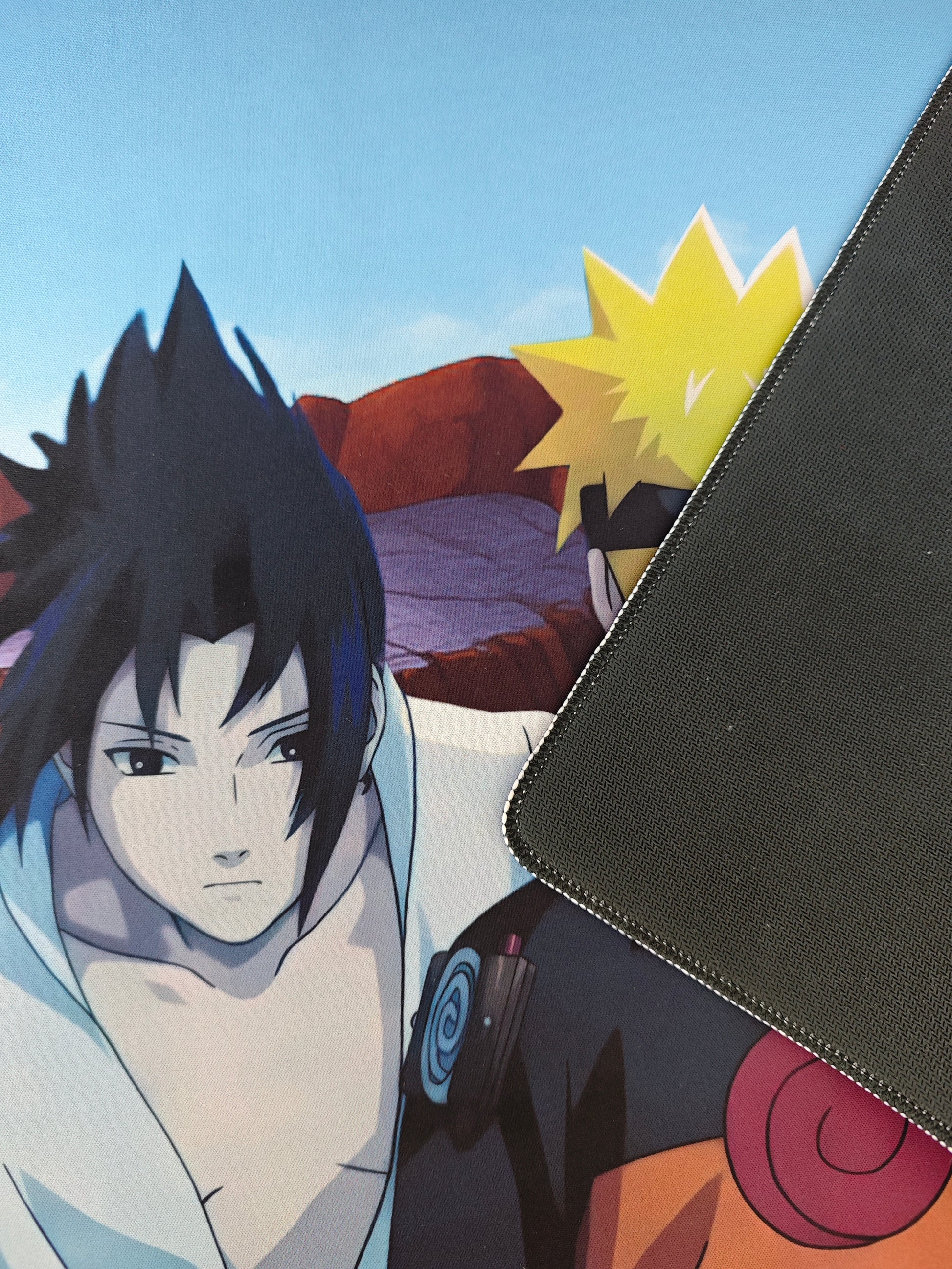 Mousepad gaming Naruto și Sasuke pe birou cu detaliu pe baza de cauciuc.